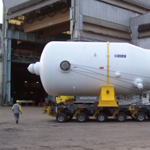 Imagem da galeria de imagem da página Nuclear. A imagem mostra um equipamento saindo da fábrica onde foi produzido. O equipamento está sendo levado por um caminhão com a ajuda de um funcionário que passa ao fundo.